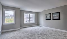 an empty room with two windows and carpet