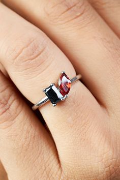 a woman's hand wearing a ring with an orange and black stone on it