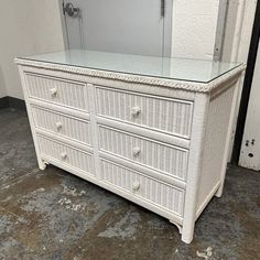 a white wicker dresser with glass top