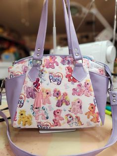 "Welcome to my Etsy listing for a custom purse, lovingly crafted with Generation 3 My Little Ponies fabric! This unique creation is a delightful fusion of nostalgia and style, perfect for any MLP enthusiast or lover of retro fashion. I've meticulously selected high-quality vinyl to complement the vibrant colors and whimsical designs of the Gen 3 fabric. The result is a durable and eye-catching purse that will withstand the test of time while turning heads wherever you go. To ensure comfort and c Handheld Bag With Removable Pouch For Personal Use, Handheld Bags With Removable Pouch For Personal Use, Handheld Shoulder Bag With Removable Pouch For Personal Use, Handheld Shoulder Bag With Removable Pouch, Detachable Handle Wallet Pouch For Everyday Use, Purple Wallets With Removable Pouch For Everyday Use, Handheld Zipper Pouch Bag For Personal Use, Wallets With Detachable Handle And Pouch Shape, Personal Use Handheld Zipper Bag