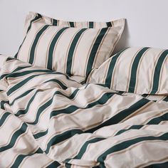 an unmade bed with green and white striped comforter on the bottom, along with two pillows