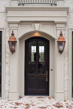 the front entrance to a house with two lights on each side