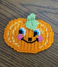 a crocheted pumpkin with a green hat on it's head sitting on a wooden table