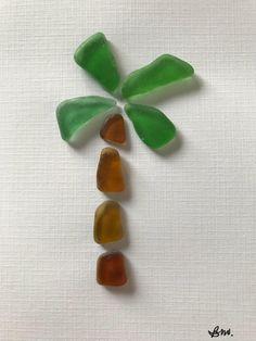 four sea glass pieces arranged in the shape of a palm tree on a white background