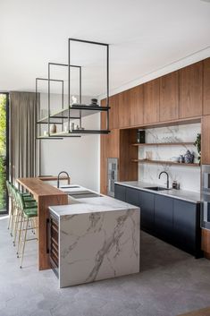 an open kitchen with marble counter tops and wooden cabinets, along with green bar stools