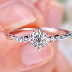 a person holding a diamond ring in their hand, with the center stone surrounded by smaller diamonds