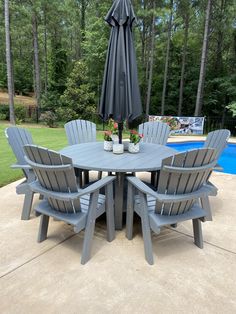 a table and chairs with an umbrella over it near a swimming pool in the backyard