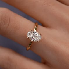 a woman's hand with a diamond ring on top of her finger, showing the center stone