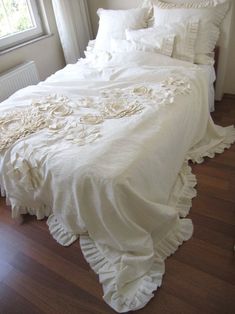 a white bed with ruffled bedspread and pillows