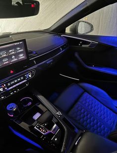 the interior of a car with blue lights and black leather seats, including an entertainment center