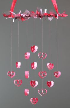 a pink mobile with hearts hanging from it's sides and ribbons attached to the strings