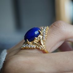 Read about our payment plans before proceeding. Elevate your elegance with the Heavenly Lapis Lazuli Ring, a stunning creation that marries the deep, celestial beauty of lapis lazuli with the timeless brilliance of white diamonds. The ring is adorned with a big natural lapis lazuli framed with natural white diamonds. Designed with a feminine antique frame, this exquisite ring is perfect for those who seek a blend of classic sophistication and modern allure. Crafted by skilled hands, this ring is Luxury Royal Blue Sapphire Ring, Elegant Royal Blue Gemstone Rings, Luxury Royal Blue Jewelry, Luxury Gold Sapphire Ring With Accent Stones, Luxury 14k Gold Sapphire Ring With Accent Stones, Luxury Royal Blue Formal Rings, Luxury Royal Blue Rings For Formal Occasions, Elegant Royal Blue Sapphire Ring As Gift, Elegant Royal Blue Sapphire Ring Gift