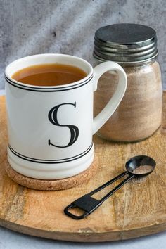 there is a cup of coffee and spoon on the tray next to it, which has a salt shaker in front of it