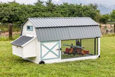 a chicken coop in the middle of a grassy field with mountains in the back ground