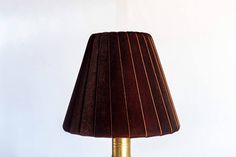 a lamp that is on top of a wooden table with a brown shade over it