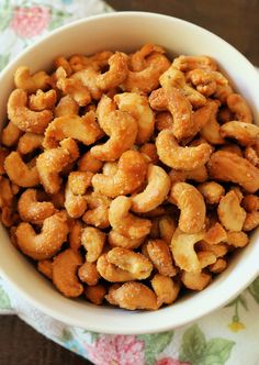 a white bowl filled with cashews sitting on top of a floral table cloth