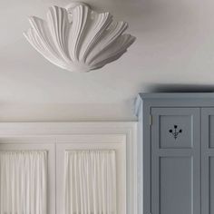 a white flower hanging from the ceiling above a cabinet in a room with gray walls