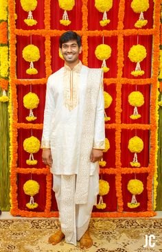 a man standing in front of an orange and yellow backdrop with flowers on it's sides