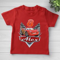 a red shirt with the number 8 on it and cars in front of it, next to a potted plant