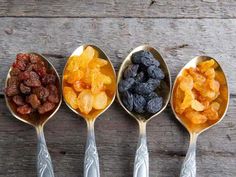 four spoons filled with different types of dried fruits