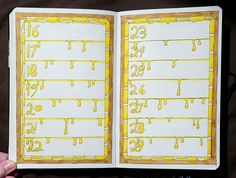 a hand holding an open notebook with yellow paint on the pages and numbers in it