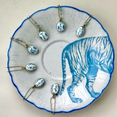 a blue and white tiger plate with several necklaces hanging from it's side