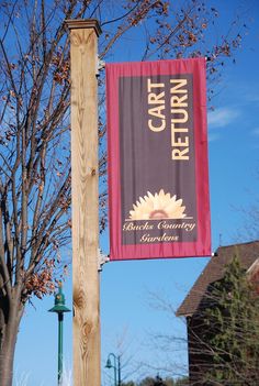 a sign hanging from the side of a wooden pole next to a tree with no leaves