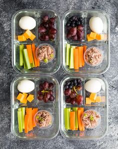 four plastic containers filled with food on top of a gray counter next to an egg