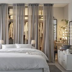 a bed room with a neatly made bed next to a dresser and window covered in curtains