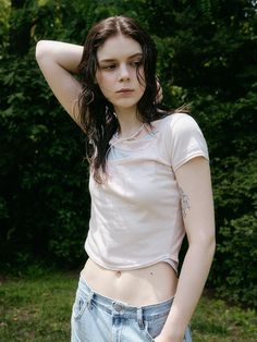 a young woman posing for the camera with her hand on her head and wearing jeans