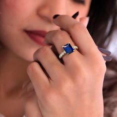 a woman wearing a blue ring with diamonds on it