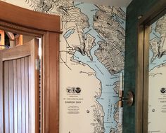 a bathroom with a map on the wall next to a wooden door and toilet paper