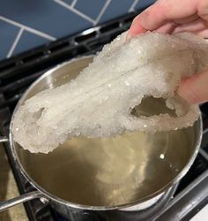 a person is stirring something in a pot on the stove top with ice and water