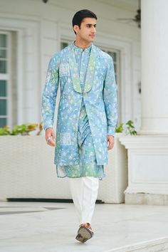 Blue silk long jacket with pintucked shawl lapel collar, patch pockets, all over floral, peacock and abstract print.
Components: 1
Pattern: Printed
Type Of Work: Floral, Peacock and Abstract Print
Neckline: Shawl Lapel Collar
Sleeve Type: Sleeveless
Fabric: 100% Silk
Color: Blue
Other Details: 
Note: The pant and kurta worn by the model is not for sale
Occasion: Sangeet,Destination Wedding - Aza Fashions Semi-formal Long Sleeve Nehru Jacket For Spring, Elegant Cotton Nehru Jacket For Spring, Blue Long Sleeve Bandhgala For Spring, Spring Formal Cotton Kurta, Designer Sherwani For Spring, Silk Bandhgala With Long Sleeves For Spring, Silk Long Sleeve Bandhgala For Spring, Spring Festive Silk Sherwani, Traditional Blue Sherwani For Spring