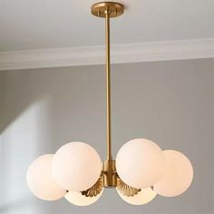 a chandelier hanging from the ceiling with five white globes on each light fixture