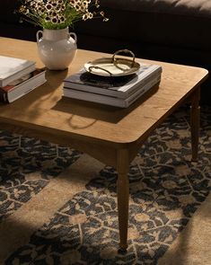 a coffee table with books on it and a vase full of flowers in the middle