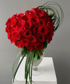 a vase filled with red roses on top of a white table