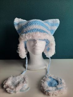 a white mannequin head wearing a blue and white crocheted cat hat