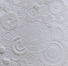 an intricate white background with circles and dots on the fabric, as well as beads