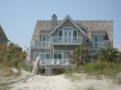 a house on the beach with sand and grass around it