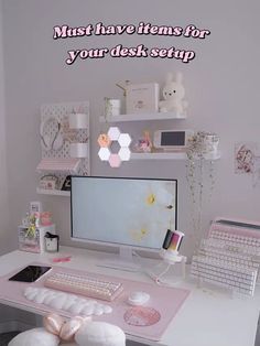 a desk with a computer, keyboard and other items on it in front of a white wall