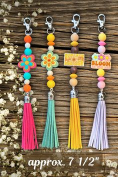 some tassels are hanging on a wooden table with flowers and the words, happy bloom