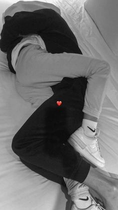 a man laying on top of a bed wearing white sneakers