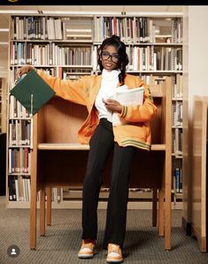 a woman sitting on a chair in front of a book shelf holding a piece of paper