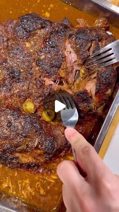 someone is holding a fork and looking at some meat on a pan that has been cooked