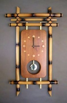 a clock made out of bamboo sticks and wood with holes in the middle, on a gray wall