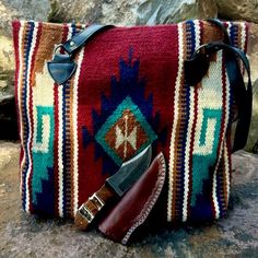 Sioux Handwoven Wool Bag with leather handles features a classic Zapotec God's Eye (Ojo de Dios) motif. It will empower your journey, as well as your outfit, with an electric blue, seafoam, orange diamond with cream butterfly centerpiece on a bold red Sky. Vibrant side panels in Native American patterns add further interest and dimension. Handcrafted handbag with Southwest and Zapotec Indian designs. Pack your journal, your favorite book, your tablet and a chocolate bar and you're set for a river adventure. With comfortable, sturdy leather handles this is a fabulous day or overnighter bag, great for a laptop, iPad, or school books! These handcrafted handbags are a Southwest style favorite and are a part of our Yellowstone Collection. #yellowstonetv @cowboysandindiansmagazine #tote #yellows Southwestern Multicolor Bags For Everyday Use, Southwestern Multicolor Everyday Bags, Multicolor Southwestern Bags For Everyday Use, Multicolor Southwestern Style Everyday Bags, Multicolor Southwestern Everyday Bags, Southwestern Style Bag With Adjustable Strap, Southwestern Style Bag With Adjustable Strap For Everyday Use, Southwestern Style Bags With Adjustable Strap For Everyday Use, Southwestern Style Rectangular Bag For Everyday Use