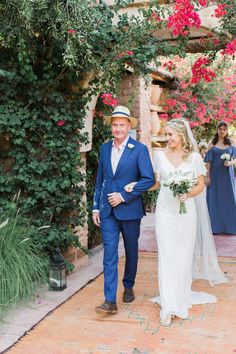 a bride and groom walking down the aisle at their outdoor wedding ceremony in an adobe - style setting