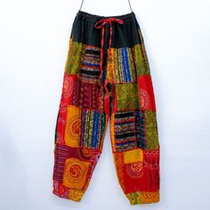 a colorful patchwork pants hanging on a white wall next to a pair of scissors