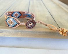 a beaded bracelet sitting on top of a wooden table next to a string tie